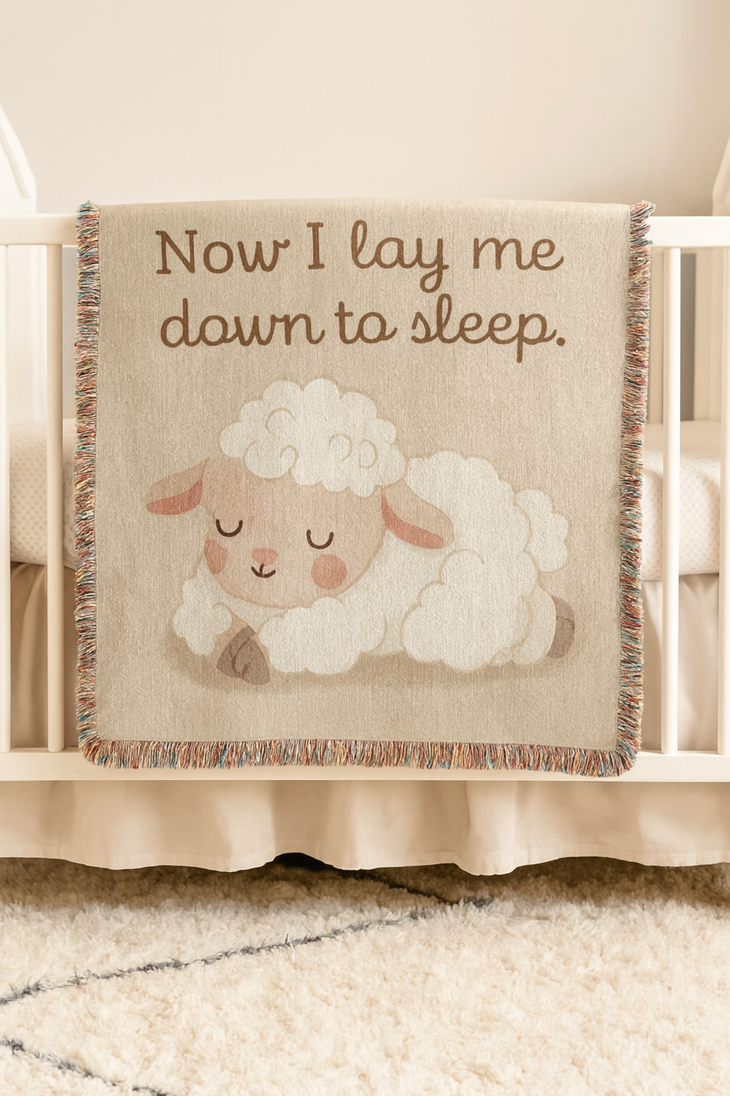 A Baby blanket hanging on a crib that reads Now I Lay Me Down To Sleep